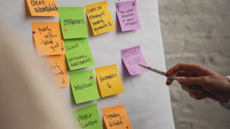 Hand pointing to post it notes on a wall