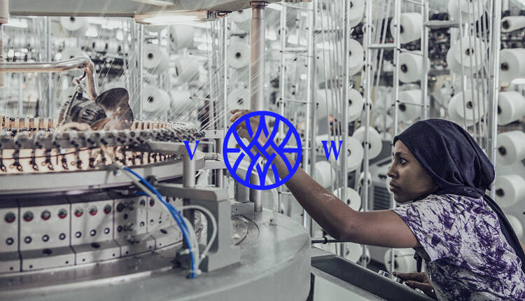 Vested world monogram logo on top of a photograph of a woman working in a factory